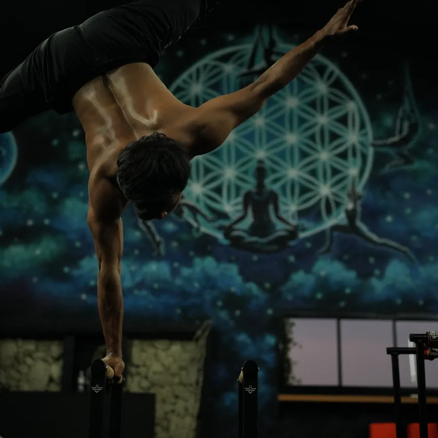 Calisthenics in Kerobokan, Bali — an athlete holding a one-arm inverted press in front of the Flower of Life mural